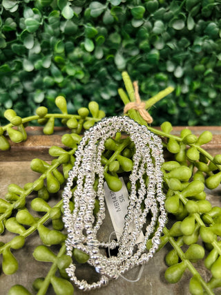 Water resistant silver beaded bracelets displayed on wooden surface with green succulent plant decoration.