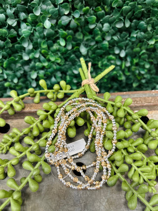 Water resistant beaded bracelets with mixed metal beads displayed on wooden surface with green succulent plants.