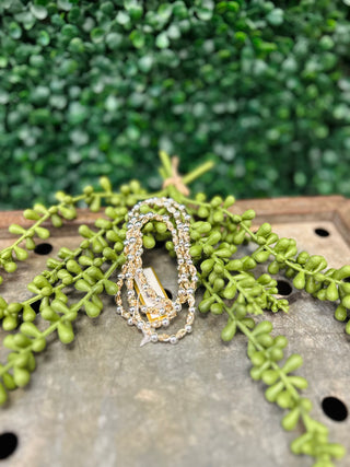 Water resistant textured oval beaded bracelets displayed on wooden surface with green foliage background.