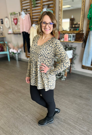Woman wearing leopard print babydoll top with long sleeves in boutique setting