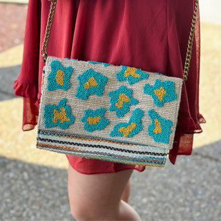 Beaded floral clutch purse with chain strap worn crossbody with red dress