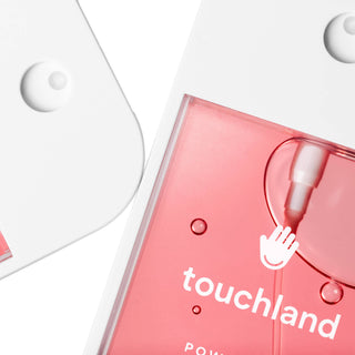 Touchland pink hand sanitizer bottle with water droplets on white background showing brand logo and hand icon