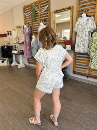 Woman wearing white lace leopard print set viewed from behind in clothing boutique showroom.