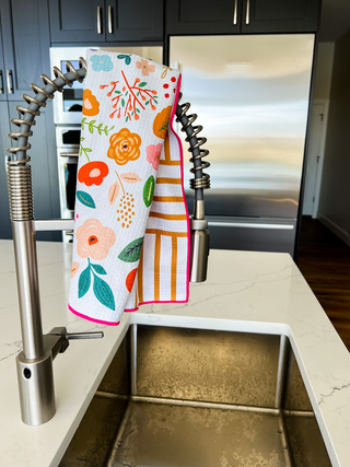 Colorful floral kitchen towels hanging on modern spring-pull faucet over stainless steel sink in contemporary kitchen