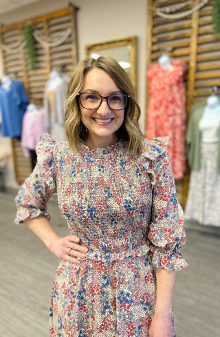 Woman wearing floral print ruffle dress with puff sleeves in clothing store setting