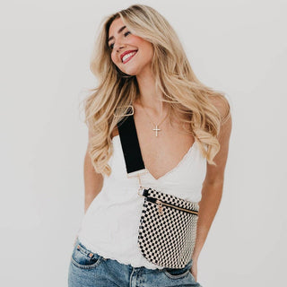Woman wearing checkered woven bum bag with crossbody strap over white tank top and jeans