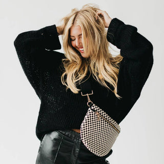 Woman wearing black sweater and leather pants with checkered woven bum bag around waist