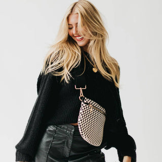 Woman wearing black sweater and leather pants with woven crossbody bum bag and gold necklace