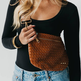 Woman wearing brown woven leather bum bag with zipper detail across black top and jeans