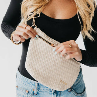 Woman wearing woven textured bum bag with gold zipper and hardware around waist over jeans