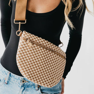 Woman wearing woven checkered crossbody bag with adjustable strap over black top and jeans