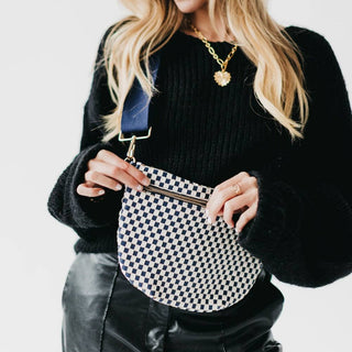 Woman wearing black sweater holding checkered pattern woven bum bag with blue strap