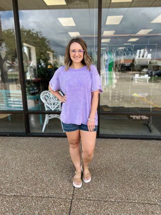 Woman wearing purple washed ribbed short sleeve top standing outside retail storefront